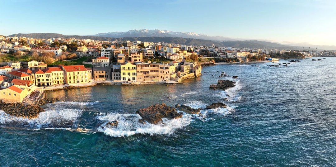 The shoreline of Tabakaria from above, with the snow-covered Lefka Ori behind the city